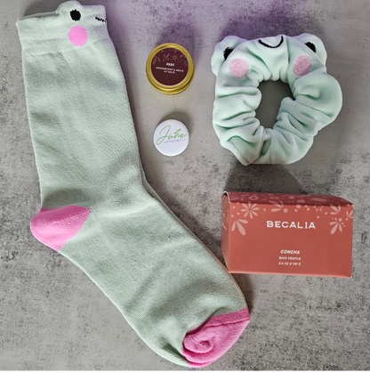 Purple June Dragonfly gift box contents: Becalia Botanicals Hibiscus Nourishing Clay Mask, Mint and Apple Froggy Socks, Mint and Apple Froggy Scrunchie, Becalia Botanicals Rebe Hibiscus Mint + Agave Lip Balm and June Dragonfly pin